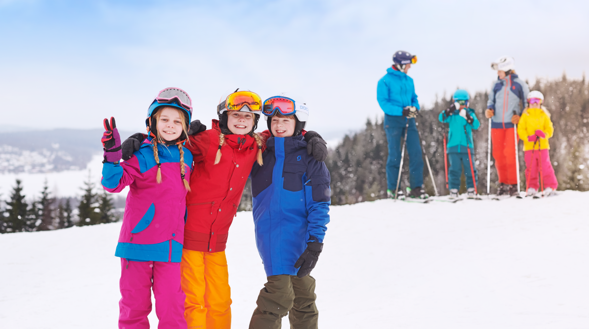 Three children in colorful clothes with skis in t on top of Ulricehamn Ski Center.