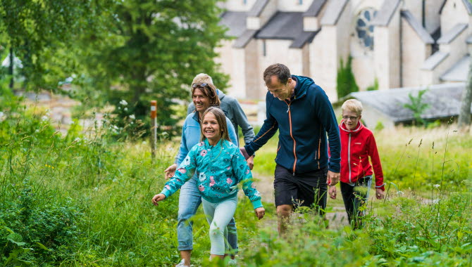 En familj ute i naturen, i bakgrunden en klosterruin.