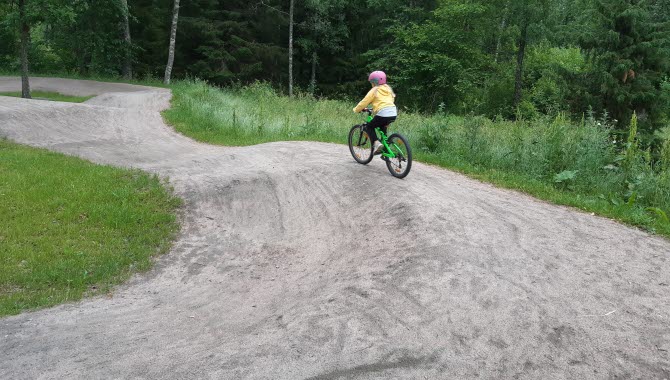 Tjej som cyklar på en grusbana.