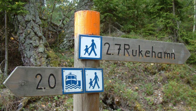 Skyltar som pekar till vandring, bad och färjeläget på Brommö i Mariestads skärgård.