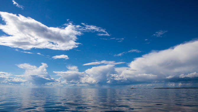 Bild på sjön med blå himmel men ett par moln