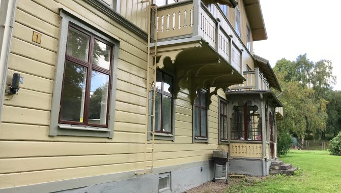 Gul stor träbyggnad med veranda.
