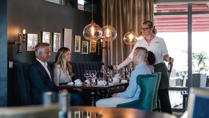 Middagssällskap som blir serverade vid bordet
