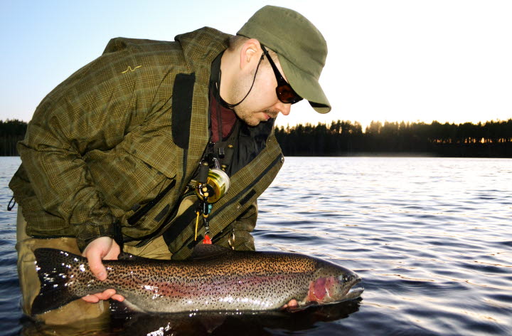 Man håller en fisk på Hökensås sportfiske.