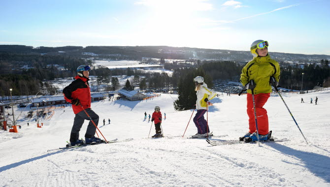 Fyra personer i färgglada skidkläder åker skidor i Ulricehamn ski center