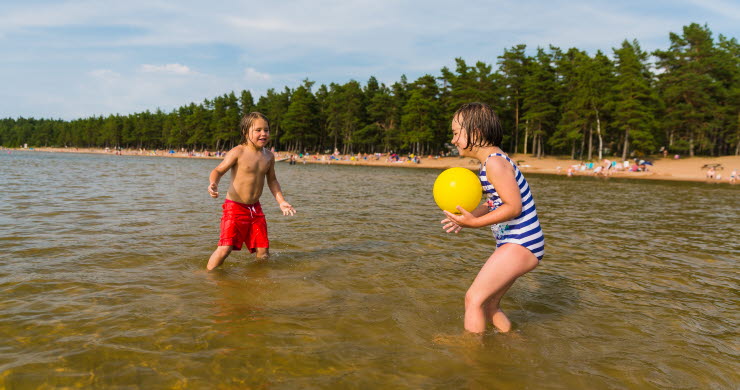 En pojke och en flicka kastar boll till varandra i vattnet. 