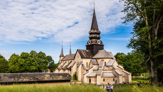 Varnhem abbey church. In the foreground you can see hikers walking towards the impressive stone church.